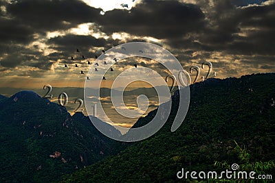 Silhoutte of flock of birds fly over the mountains on the background of the sunrise Stock Photo