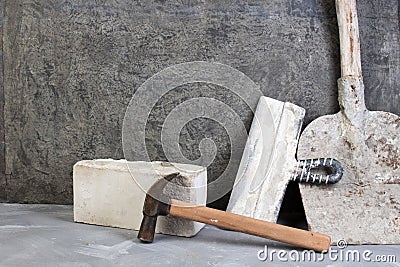 silicate bricks, hammer, putty knife, old, dirty shovel on the gray concrete background. Copy space. Top view Stock Photo