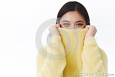 Silly and cute asian girl laughing while pulling collar on face, giggle coquettish smiling with eyes as looking camera Stock Photo