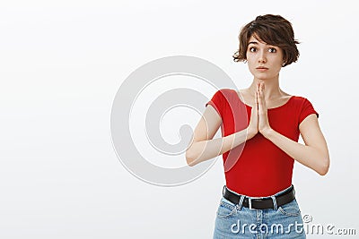 Silly cute timid woman short haircut press palms together supplication pray look innocent tender asking help begging Stock Photo