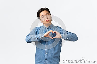 Silly handsome asian young guy in blue shirt confessing love, express sympathy, blogger grateful for followers, showing Stock Photo