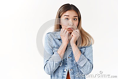 Silly insecure timid asian blond girl feel unsafe scared shivering fear hold hands close mouth sulking frowning innocent Stock Photo