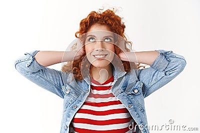 Silly playful good-looking redhead girl curly hairstyle close ears press hands head look up delighted smirking standing Stock Photo