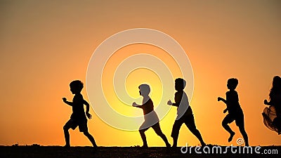 Silueta de cinco niños que corren contra puesta del sol Silueta de cinco niños que corren contra puesta del sol