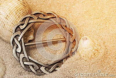 Silver antique old Celtic scarf ring with traditional design border in sand.. Hand made traditional jewellery Stock Photo