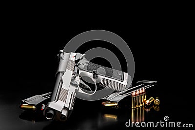 Silver black modern gun and ammunition for it on adark back. Short-barreled weapons for sports and self-defense. Armament for Stock Photo