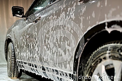 The silver car in the foam on the side focuses on the flowing liquid on the doors and windows Stock Photo