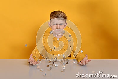 Silver coins are falling on the table to the child in an orange T-shirt Stock Photo