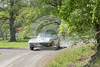 Silver color Chevrolet Corvette Convertible classic car from 1964 driving on a country road Editorial Stock Photo