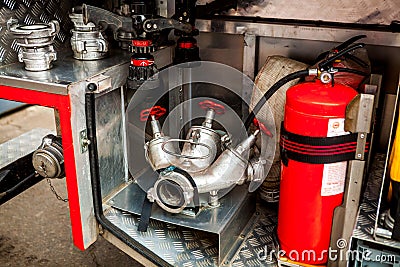 a silver-colored fire hydrant with red valves and other fire equipment lies in fire car. red extinguisher Stock Photo