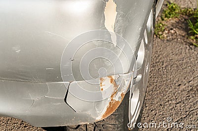 Silver damaged car in crash accident or collision with scratched paint and dented rear bumper metal body Stock Photo