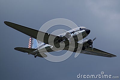 Silver Douglas C-47 Skytrain soaring in the sky against white clouds Editorial Stock Photo