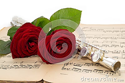 Silver flute and beautiful red rose on an ancient music score Stock Photo