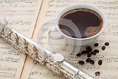 Silver flute, cup of coffee and coffee beans on an ancient music score Stock Photo