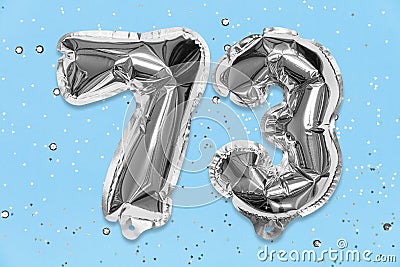 Silver foil balloon number, digit seventy three on a blue background with sequins. Birthday card with inscription 73 Stock Photo