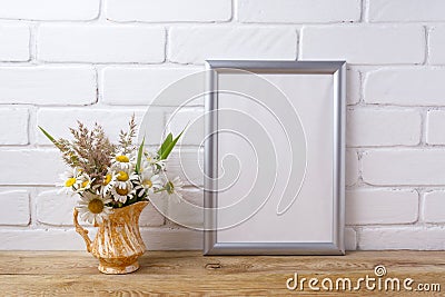 Silver frame mockup with chamomile and grass in golden pitcher Stock Photo