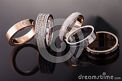 Silver, gold, platinum rings of different styles on the dark background of reflections Stock Photo