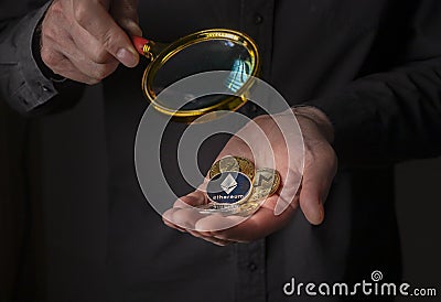 Silver and golden coins of cryptocurrency in male hand palm over black background, close up. Pile of ethereum, monero Editorial Stock Photo