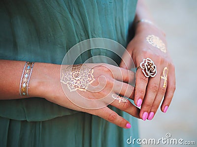 Silver and golden flash tattoo on female hands over sea or ocean background. close up hands with boho gypsy gold Stock Photo