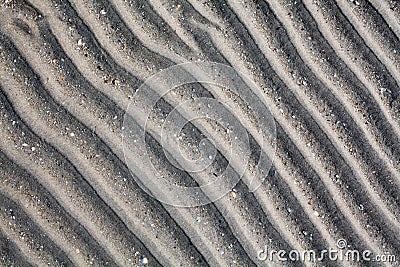 Silver gray sand on sea beach top view close up, ribbed dry sand surface pattern, wavy curved diagonal lines texture Stock Photo