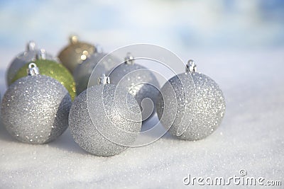 Silver, green and gold Christmas baubles in snow Stock Photo
