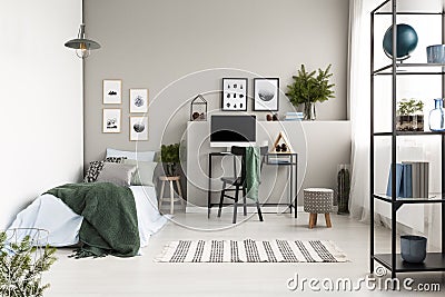 Silver, green and patterned pillow on blue bedding on single bed with green blanket in modern forest inspired bedroom, real photo Stock Photo