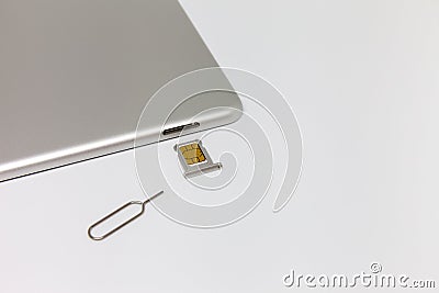 Silver inverted tablet. The SIM card tray is open. Stock Photo