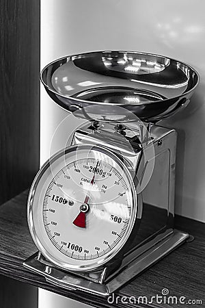 Silver kitchen scales with a red arrow on the shelf Stock Photo