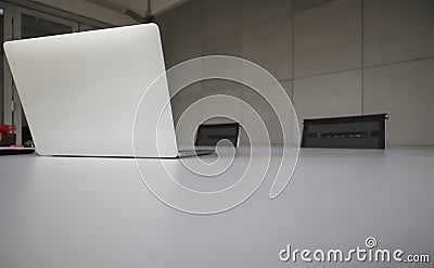 Silver laptop places on the white office table with mobile phone, pencils and others. Stock Photo