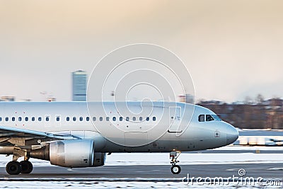 Silver passenger airplane taxiing on runway to take off in winter day, side view Stock Photo