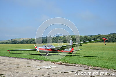 Silver and red glider stands on grass landing strip in small country airport while the weather is nice Editorial Stock Photo