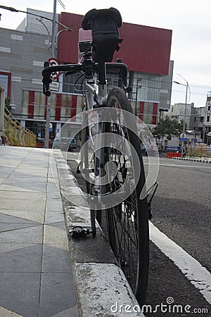 A silver road bike leaning onto a side road Stock Photo