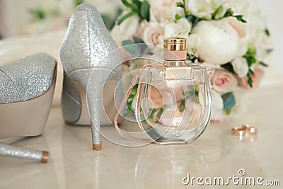 Silver shoes of the bride , perfume, bouquet and wedding rings on the dressing table near the mirror. Stock Photo