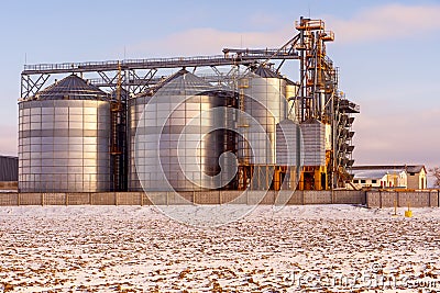 Silver silos against the blue sky in winter. Grain storage in winter at low temperatures. Production for processing, drying, Stock Photo