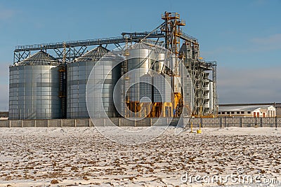 Silver silos against the blue sky in winter. Grain storage in winter at low temperatures. Production for processing, drying, Stock Photo