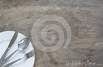 Silver spoon, fork and knive in plate on old, rusty, wooden back Stock Photo