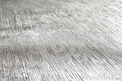 A silver textured surface with a smooth, matte finish, featuring faint, linear patterns that add a Stock Photo