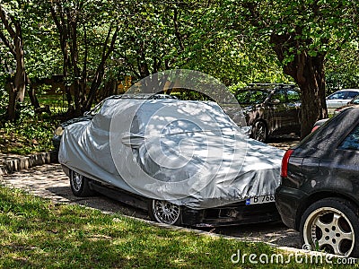 Silver weatherproof cover on a stationary car parked outdoors. Modern car covers protect from heat, rain, dust and UV Editorial Stock Photo