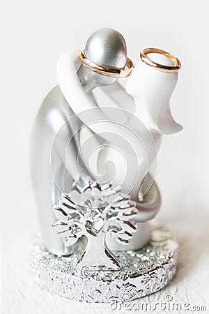 Silver and white figurine of couple - man and woman - with golden wedding rings Stock Photo