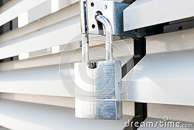 Wavy metal door of an industrial building with locked padllock during quarantine.solar reflections.Outdoor shoot Stock Photo