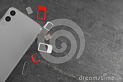 SIM cards, mobile phone and ejector tool on grey table, flat lay. Space for text Stock Photo