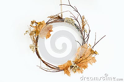 Simple autumn wreath hanging on white wall. Modern rustic autumn wreath made of branches, twig, fall leaves, dried herbs and Stock Photo