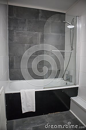 Simple bath with overhead shower in bathroom in natural stone tiled bathroom. Stock Photo