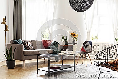 Simple brown sofa with cushions in an eclectic, white living room interior with natural light coming through big windows. Stock Photo