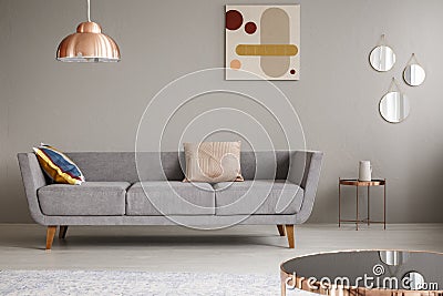 Simple couch with pillows in a living room decorated with copper lamp, mirror and painting Stock Photo