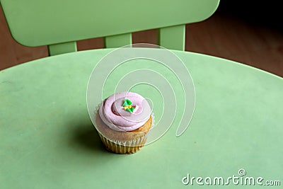 Simple green table and chair with one strawberry cupcake with thick, creamy frosting Stock Photo