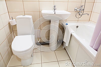 Simple half bathroom with toilet, sink and bath with shower, white sanitary ware Stock Photo
