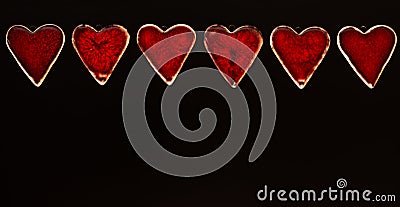 A row of ceramic red Valentines hearts on a matt black background Stock Photo