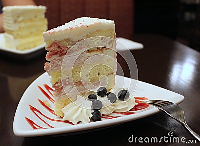 Simple white plate with huge slice of cake filled with berries and cream Stock Photo