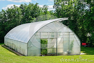 Simple wide plastic greenhouse with a open window in countryside home garden Stock Photo